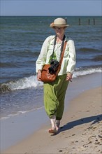 Elderly woman walking barefoot on the beach, Darßer Ort, Born a. Darß, Mecklenburg-Vorpommern,