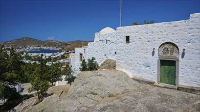 View of a white church on a rock overlooking a coastal landscape and blue sky, Monastery tis