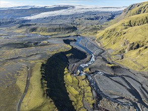 River along road F232 Öldufellsleid, slopes of Mt. Öldufell, moss-covered hill in black lava sand,