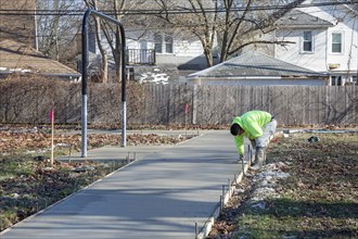 Detroit, Michigan - Workers pour and finish concrete for walking paths in Three Mile Park in