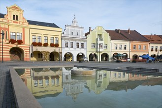 Colourful house facades with reflection in the water basin, sunny Bohemian market atmosphere,