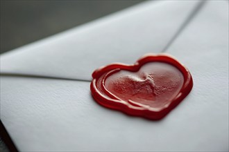 Close up of red heart shaped wax seal on white love letter. Generative AI, AI generated