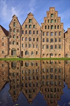 Historic salt warehouses, brick buildings reflected on the water surface of the Trave, blue sky