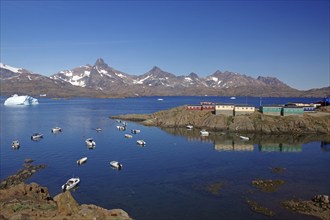 View of small boats in calm fjord, with mountains and colourful houses in the background, Knud