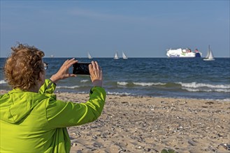 Older woman taking photos of boats, sailing boats, ferry, smartphone, Kieler Woche, Falckensteiner