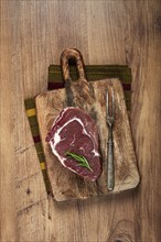 Raw steak, beef steak, rib eye steak, on a cutting board, freshly frozen, with spices and herbs, on