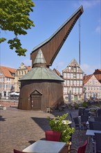 Old crane with outdoor area of a restaurant and historic half-timbered houses in the Hanseatic