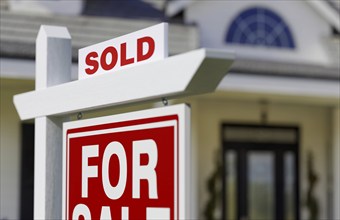 Sold for sale real estate sign in front of new house.