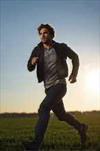 Man sprinting across an open field sunset, AI generated