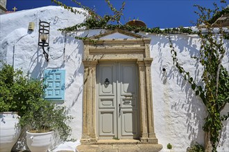 A building with a decorated stone entrance and surrounded by plants under a blue sky, Chora, Old