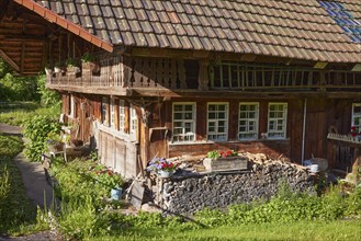 Details of an old Black Forest house with woodpile, windows, balcony and planters in the historic