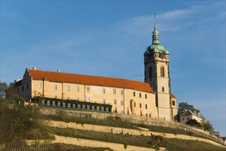 Historic castle with tower on a hill under a blue sky in the evening sun, Melnik Castle, Church of