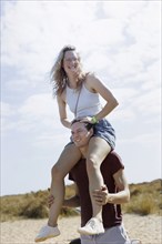 Man carrying woman on his shoulder, North Sea island of Borkum, 18.05.2024