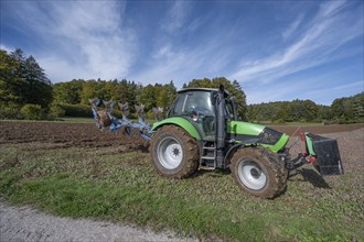 Farmer with tractor ploughing his field with a 5-turn rotary plough, Franconia, Bavaria, Germany,