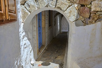 Narrow passageway with stone walls and a blue door, traditional Greek style, Chora, Old Town,