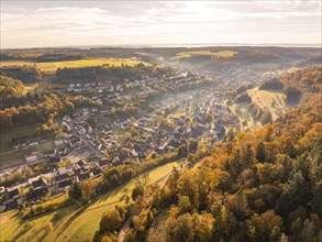 Autumnal aerial view of a village with colourful trees, fields and hills at sunset, Sulz Calw,