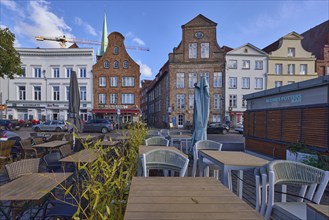 Outdoor area of a restaurant with tables, chairs and parasols, historical building, gable, street