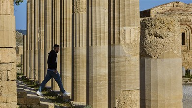 A man walks through ancient columns radiating tranquillity and historical significance, Acropolis