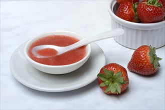 Strawberry sauce in small bowls and strawberries, strawberry coulis