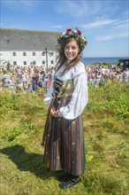 Young woman with a flower wreath on her head and dressed in folk costume from Smyge at a