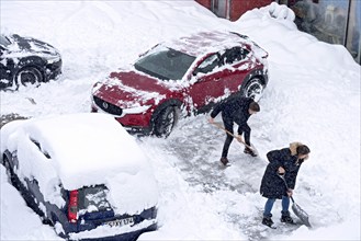 Man and woman shovelling snow on car park, car, car, snowed in, fresh snow, heavy snowfall, snow