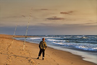 Surf fishing, angler standing with two rods on the beach, Soustons Plage, evening light, Silver