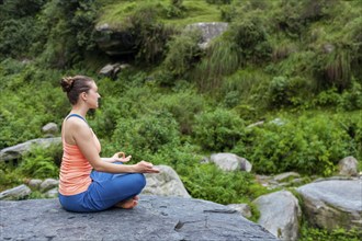 Woman in Hatha yoga asana Padmasana outdoors