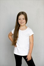 Cute young child with long hair in white t-shirt and black sweatpants posing