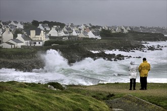 Tourists looking at winter storm at sea at Pors Poulhan, Plouhinec, Morbihan, Brittany, France,