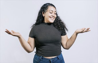 Smiling latin woman comparing with palms hands isolated. Happy girl balancing product with palms