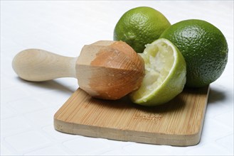 Limes and squeezed lime with citrus press on cutting board