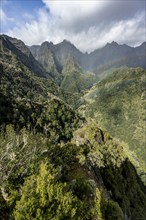 Densely overgrown steep mountains with rainbow, green mountain landscape, view from Miradouro dos