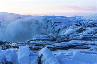 Icefall at the edge of the Godafoss waterfall at dawn, snow-covered landscape, Northern Iceland