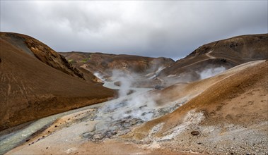 Hot springs and steaming stream between colourful rhyolite mountains, Hveradalir geothermal area,