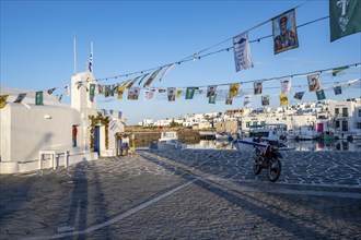 White Cycladic Greek Orthodox Church of Agios Nikolaos, decorated with flags, harbour of Naoussa,