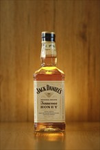 2021, 23 February, Minsk, Belarus, glowing Bottle of Jack Daniel's honey on wooden background (soft