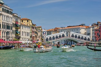 VENICE, ITALY, JULY 19, 2019: Rialto bridge with boats and gondolas passing under on Grand Canal,