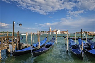 VENICE, ITALY, JUNE 27, 2018: Gondolas and gondolier in lagoon of Venice by Saint Mark (San Marco)