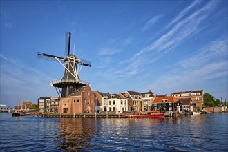 Harlem cityscape, landmark windmill De Adriaan on Spaarne river with boats. Harlem, Netherlands