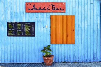 Colourful hut, wooden facade of a bar with orange closed shutter and menu, advertising alcoholic