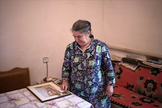 A Crimean Tatar woman in her home looks at a picture of her family's house in front of deportation