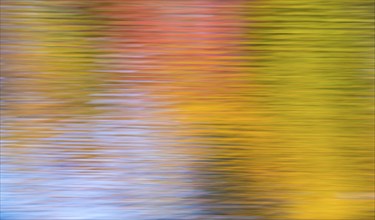 Colourful autumn leaves and blue sky are reflected in the water of the Bockelsberg ponds, small