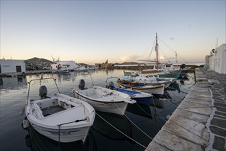 Fishing boats in the harbour of Naoussa at sunset, White Cycladic houses, Naoussa, Paros, Cyclades,