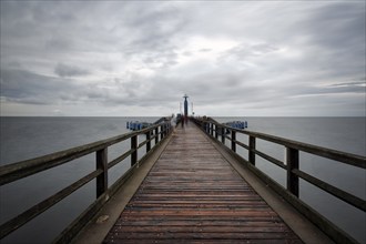 Pier Sellin with single tourists in front of diving gondola, rainy weather at the Baltic Sea, long