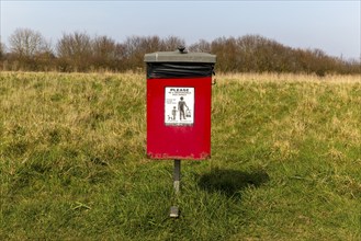 Red dog waste bin, Cudmore Grove Country Park, East Mersea, Mersea Island, Essex, England, UK