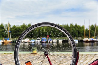 View through the spokes of a bicycle at boats on the river, symbolic image, repairing a bicycle,