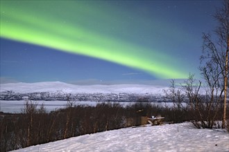 Northern lights (aurora borealis) in wintry landscape over a frozen lake Abisko National Park,