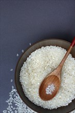 Rice, white rice grains and wooden spoon in bowl