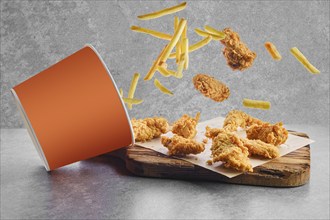 Deep fried chicken wings and nuggets in breading scattered from basket on parchment paper