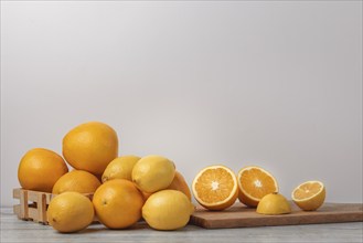 Basket and wooden board with oranges and lemons, vitamin C, light background, copy room